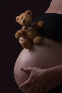gros plan sur le ventre d'une femme enceinte avec un ours en peluche studio photographe tours photographe grossesse tours studio photo tours photographe mariage tours